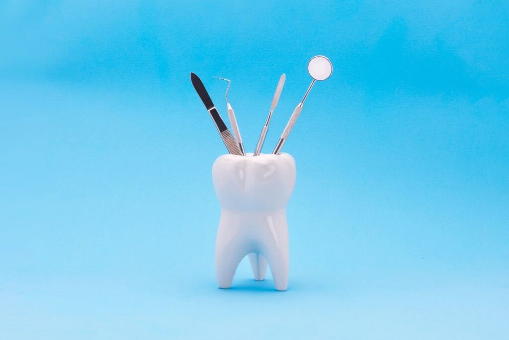 A tooth shaped holder with toothbrushes and an empty toothbrush.