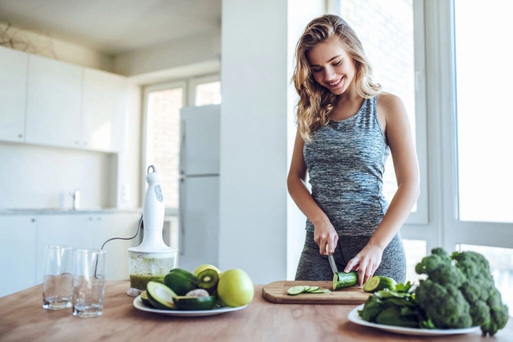 A woman cutting up vegetables on top of a wooden table.