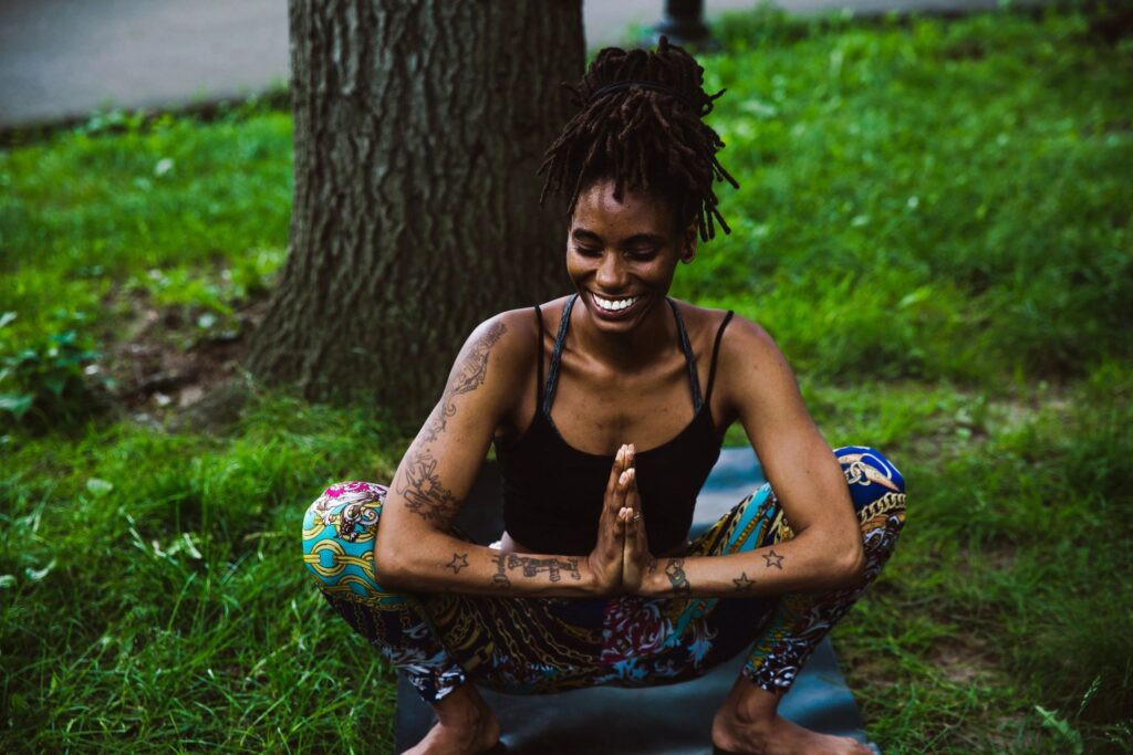 A woman sitting in the grass with her hands folded.